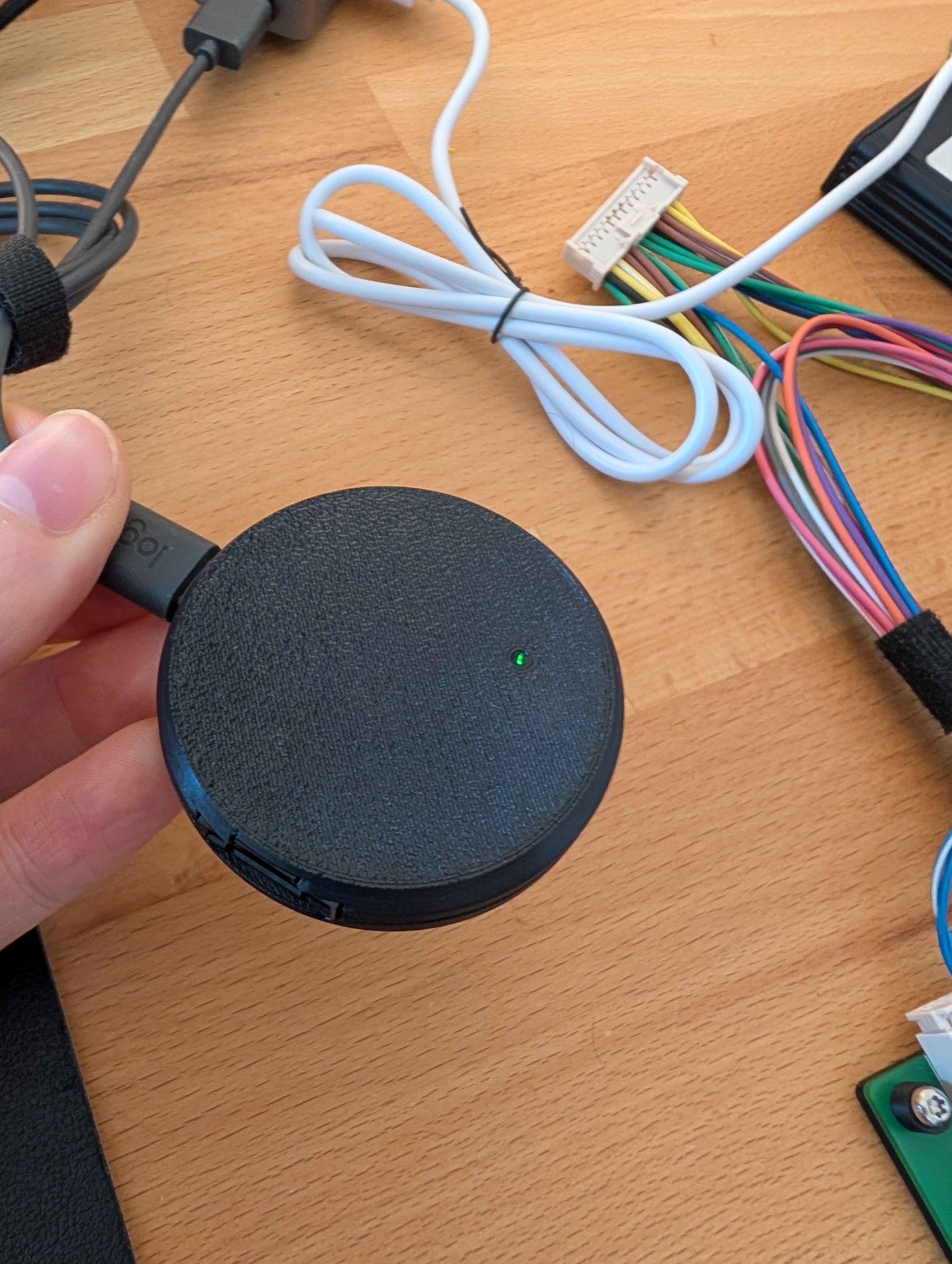 The DashKit device — a compact round module with a status LED and CAN-FD harness